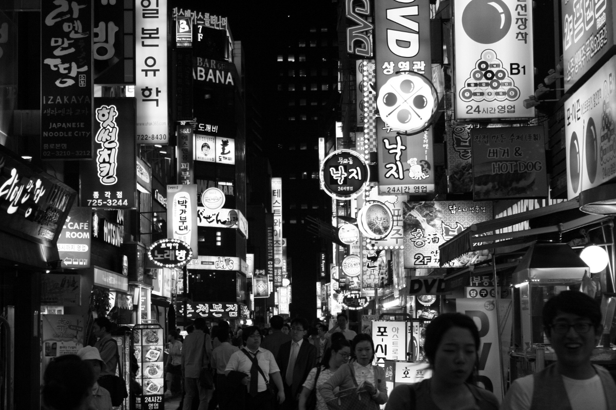 a crowded city street at night with signs lit up