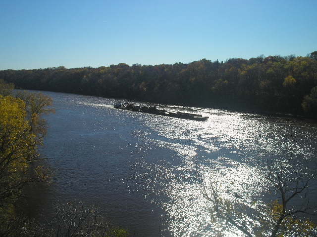 many barges are floating down the river surrounded by woods