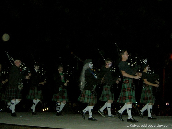 a group of kilt - clad men performing on a street at night