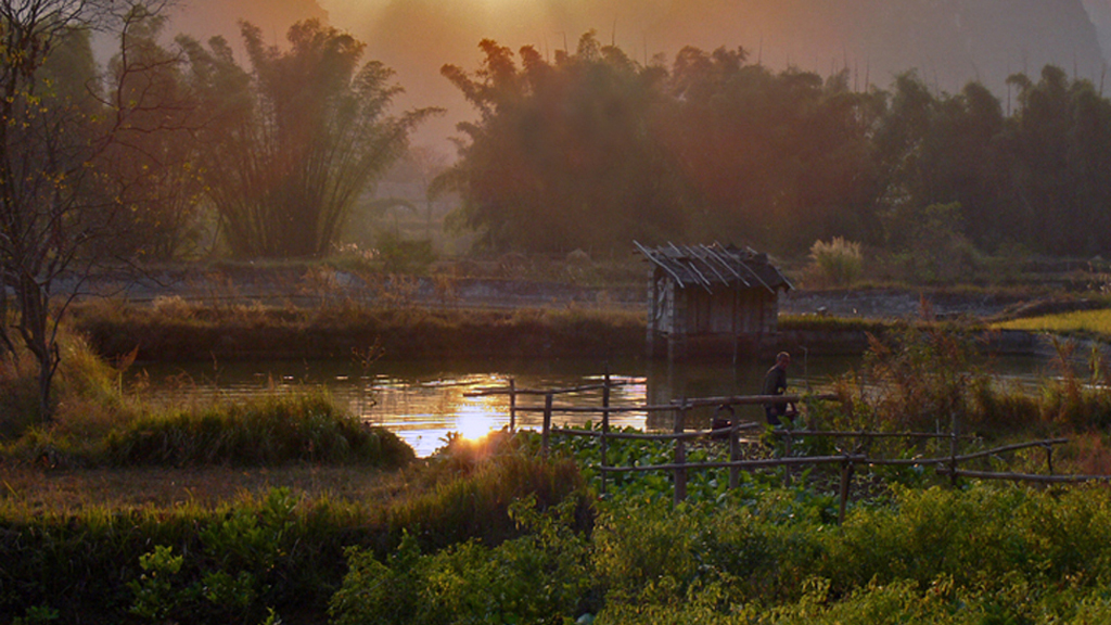 some houses on the edge of a lake at sunset