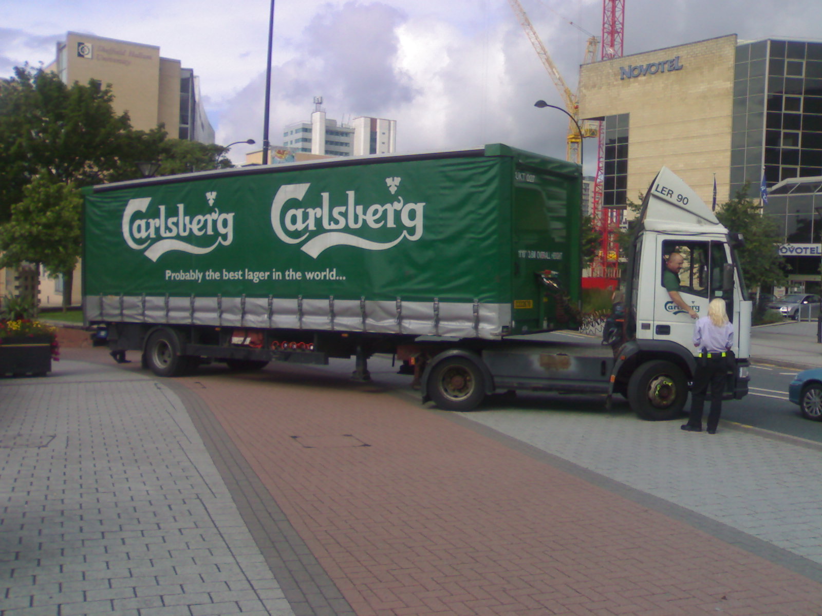 large green truck driving down the street next to cars