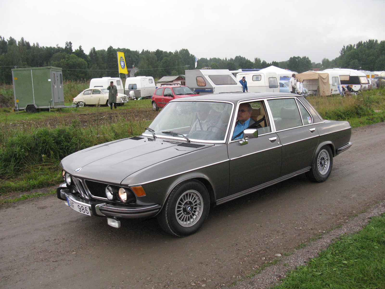 an old grey bmw sits on the side of the road