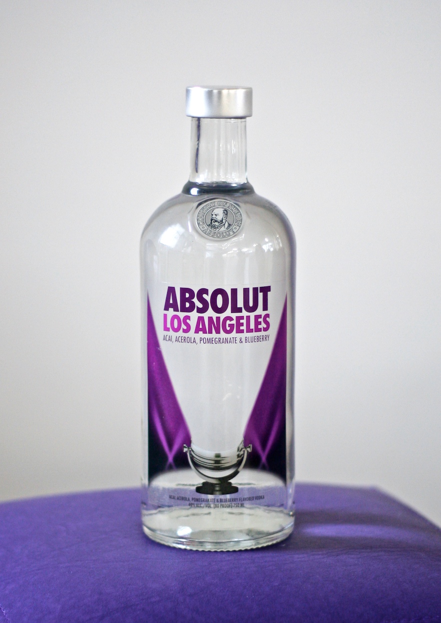 a bottle of absolut los angeles alcohol sitting on top of purple table cloth