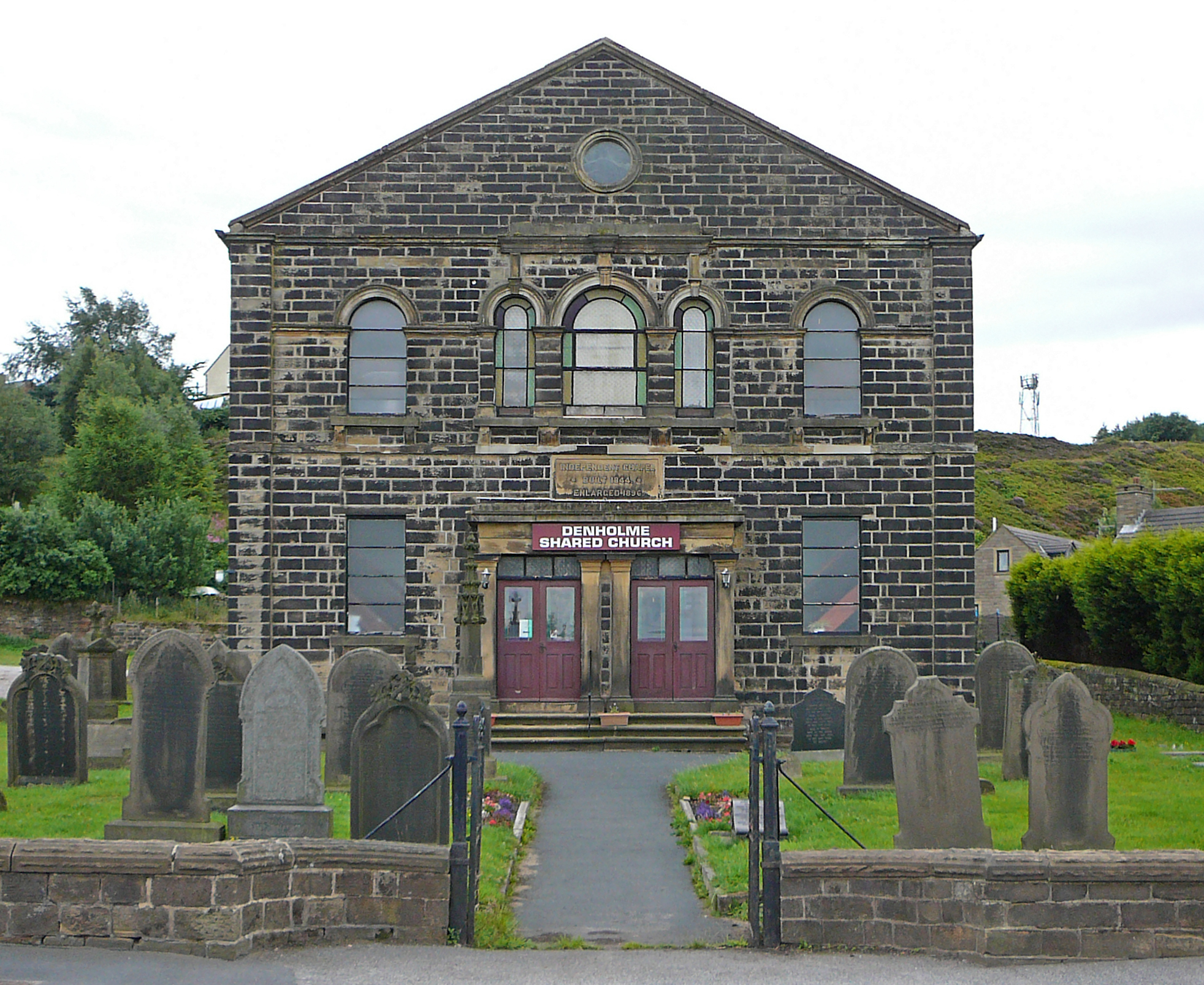 an old brick building has a cemetery next to it