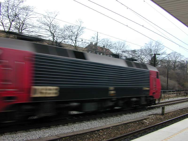 a red and black train on train tracks near a building