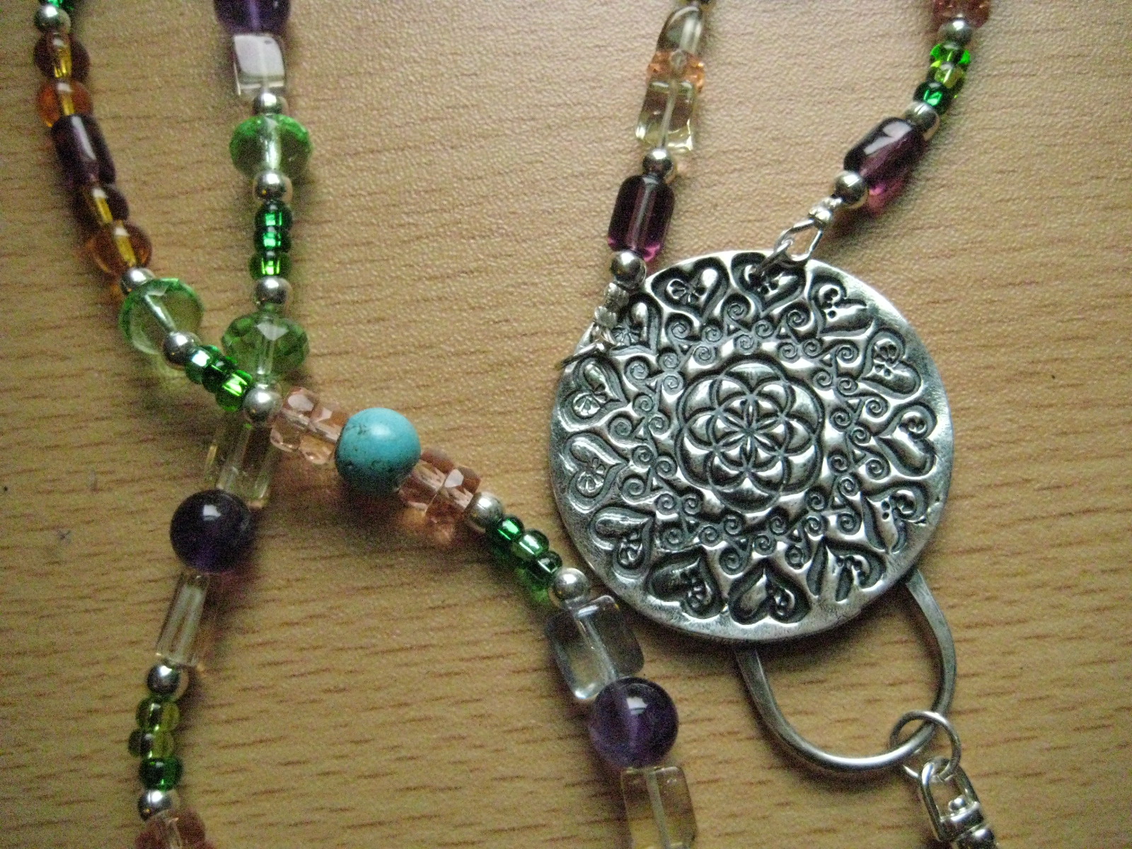 a silver medallion with a flower and some other beads