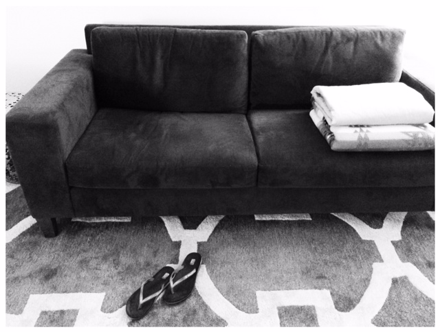 a couch sitting in front of a wall on top of a rug