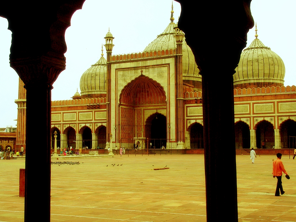 view from a building through some pillars with people on the floor