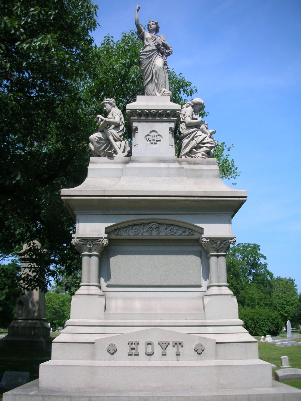 a statue sitting in front of a green tree