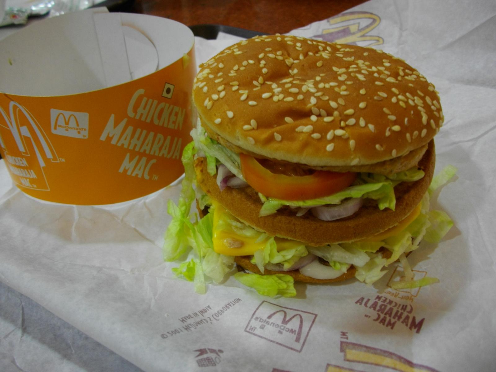 a large hamburger with lettuce and tomatoes is next to a drink
