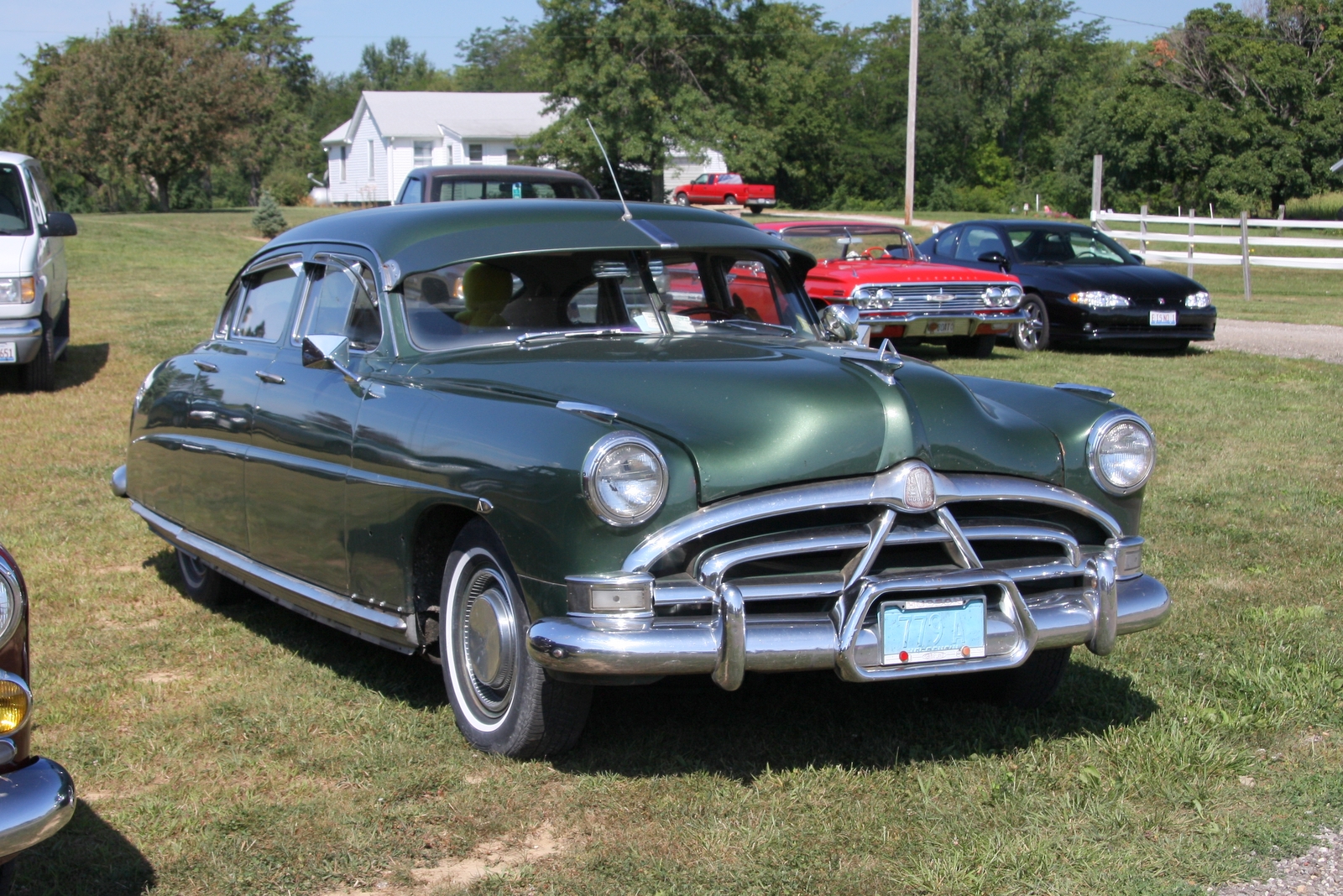 two old cars parked in a grass lot