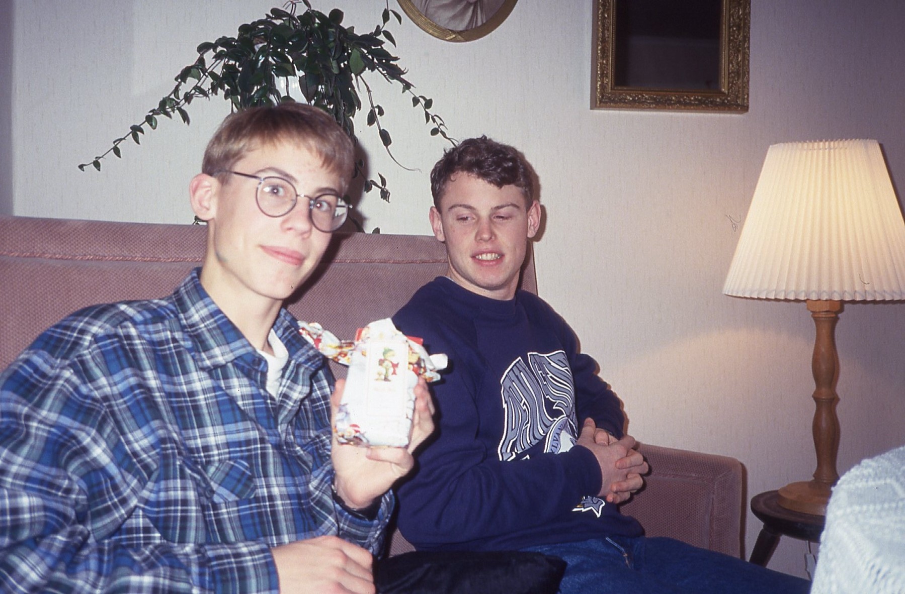 two men sitting on a couch, one holding an object