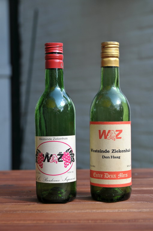 two wine bottles, one green and the other pink are placed next to each other
