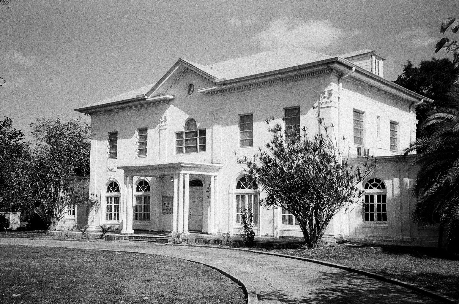 an old po of a house with trees and cars