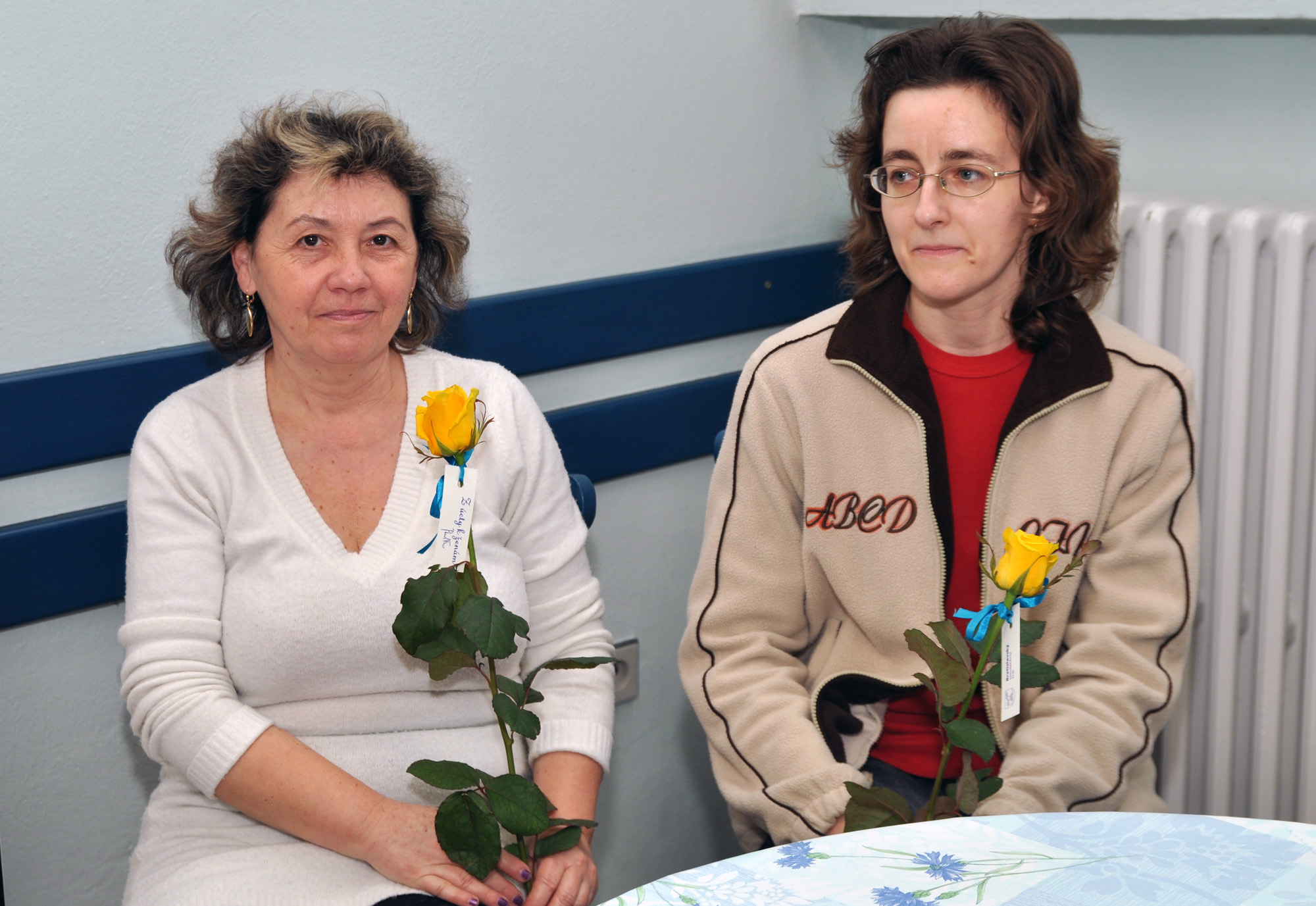 two women sitting at a table in front of each other with flowers on them