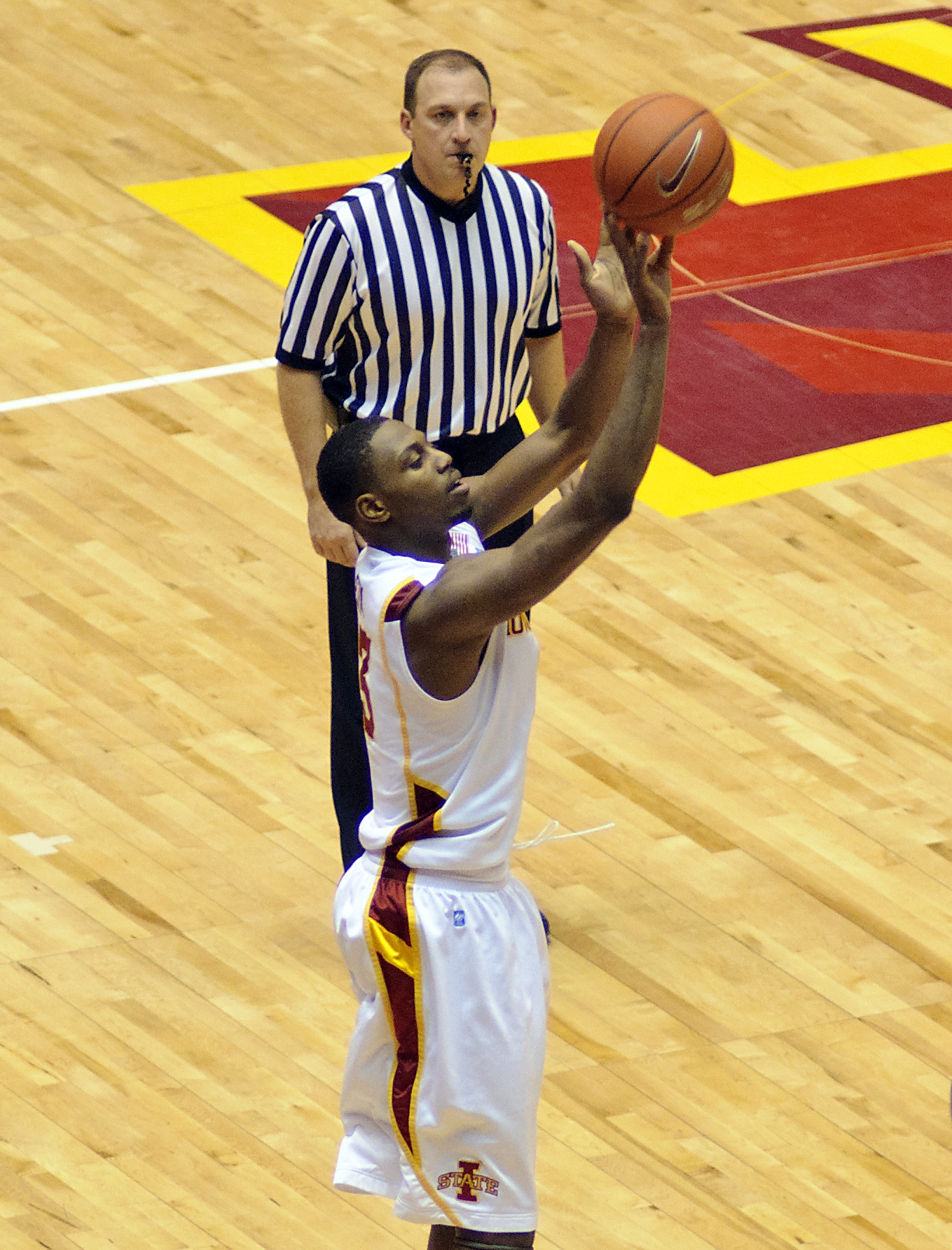 a referee standing next to a basketball player holding a ball