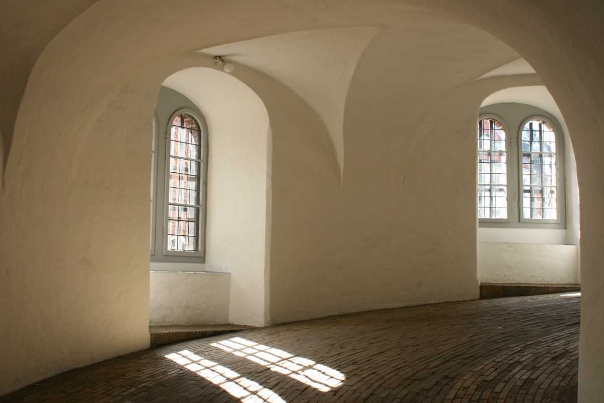 a room with large arched windows and tile floor