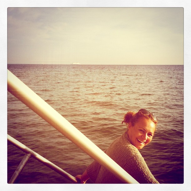 a woman is standing on the edge of the boat in the water