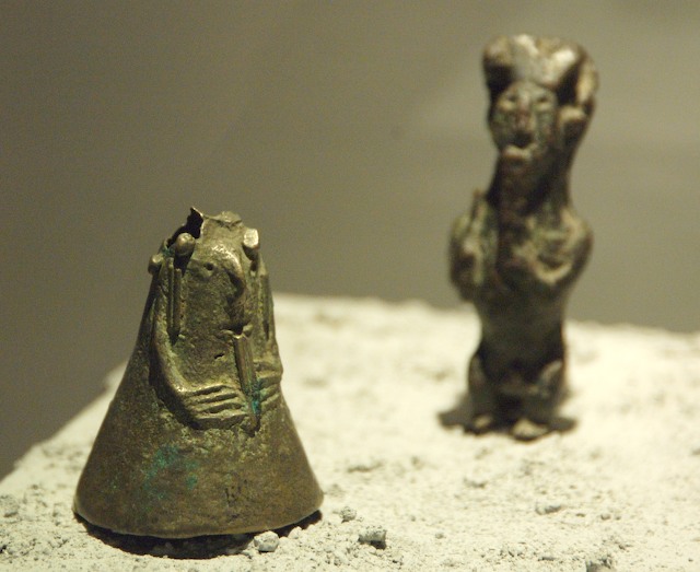 two bronze figurines stand together near each other