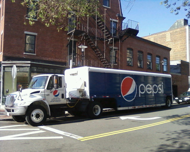 pepsi truck on the side of a street in front of buildings