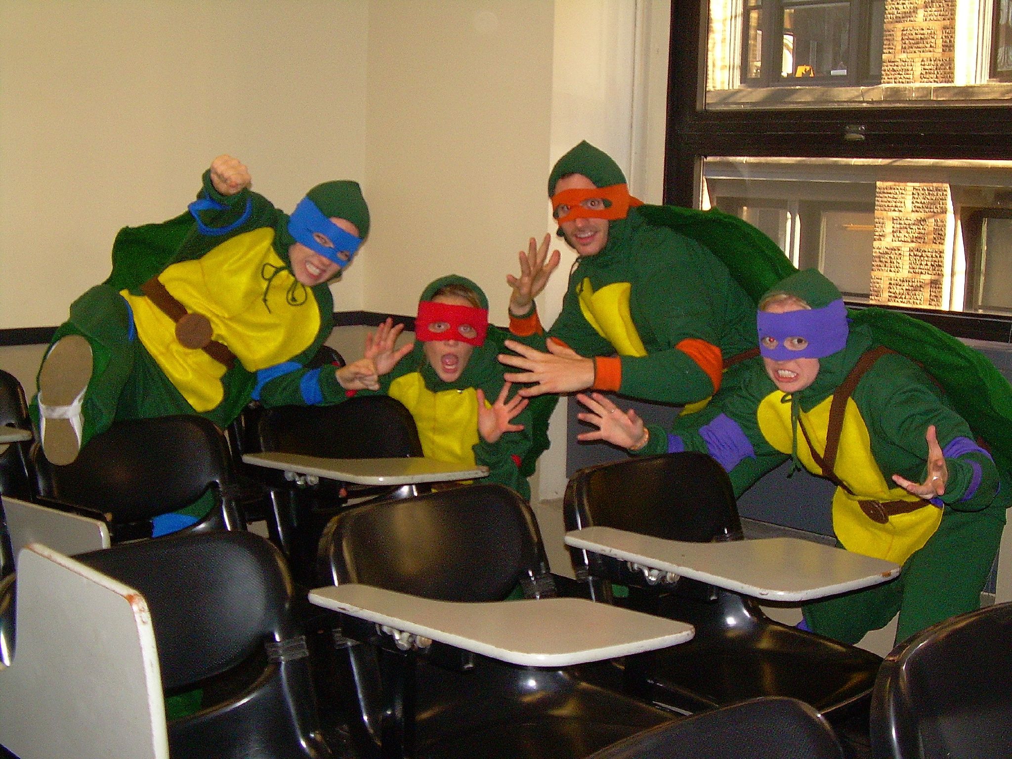 three s wearing ninja costume sit in a classroom