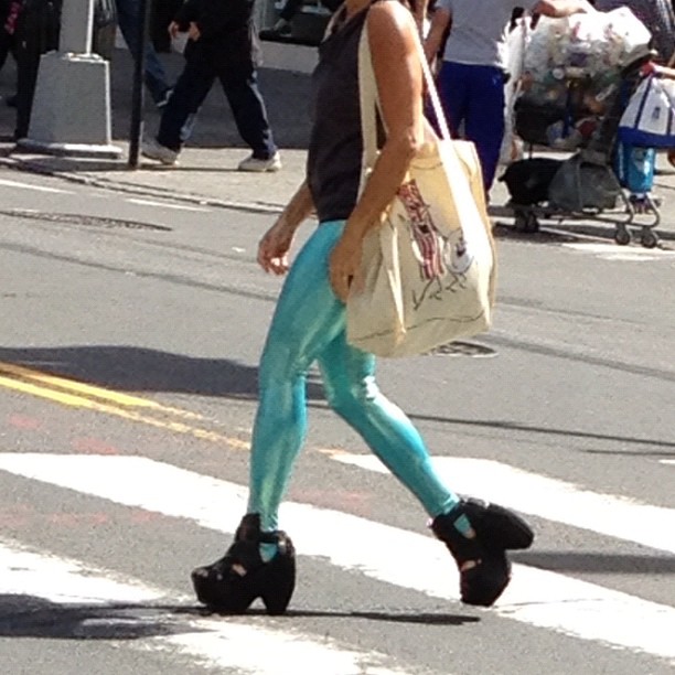 the woman with a purse is crossing the street