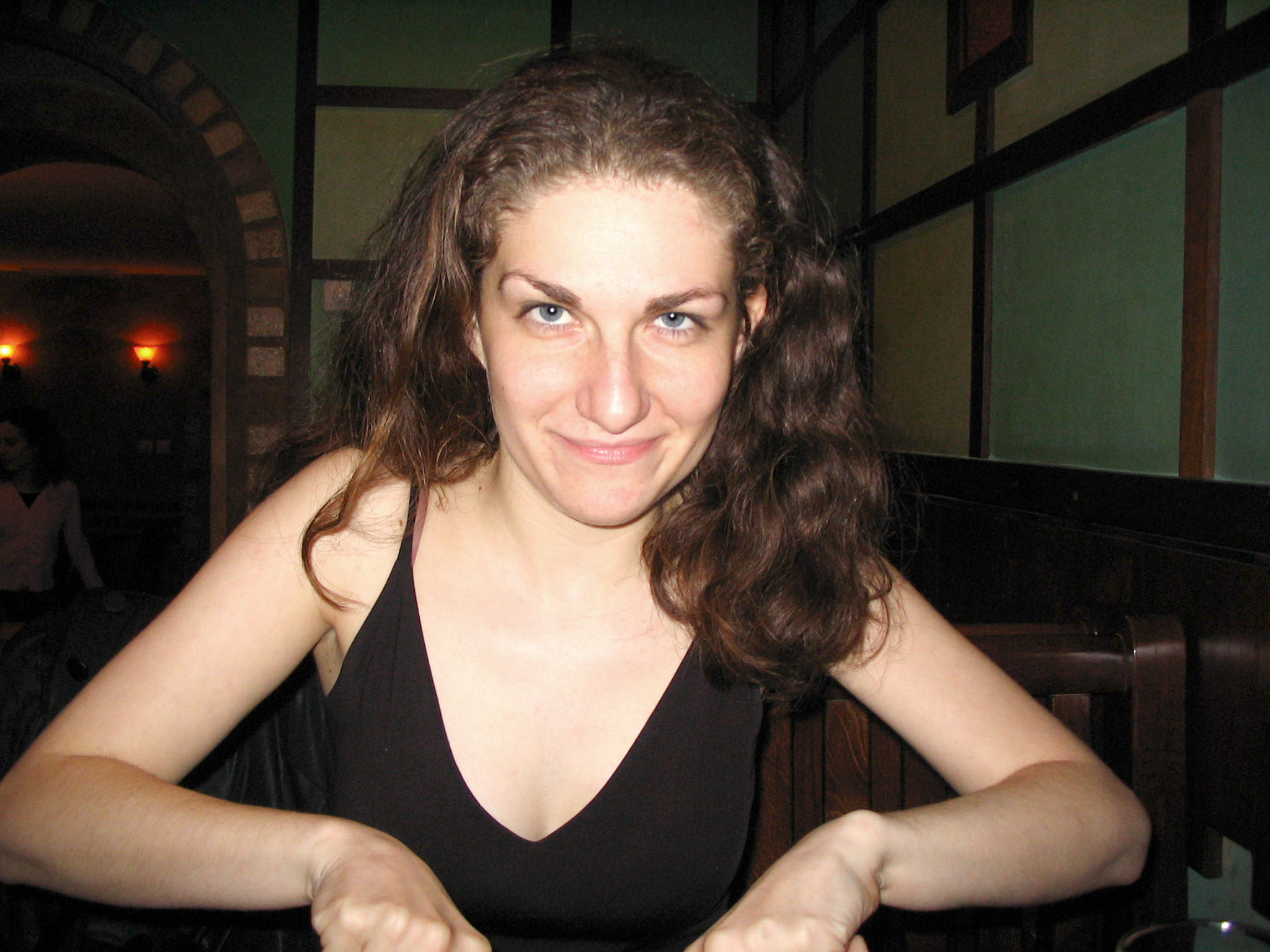 a woman is smiling at the camera, in a restaurant