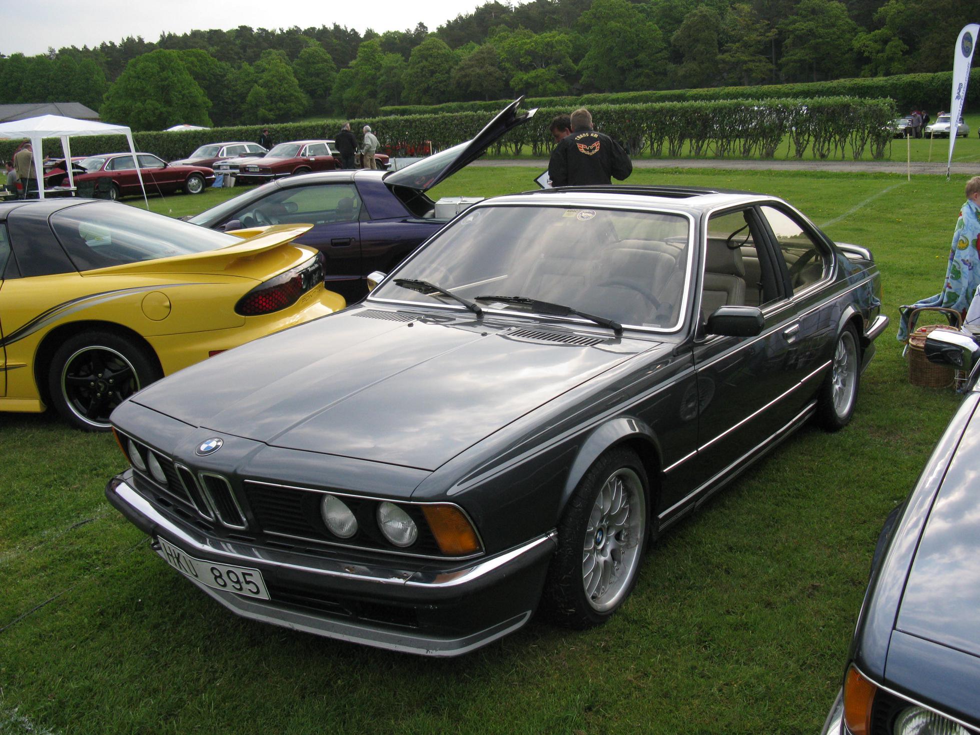 a silver car parked next to other cars on a field