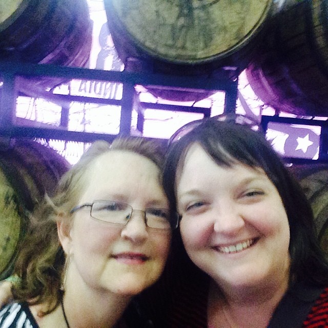 two women smiling in front of wine barrels