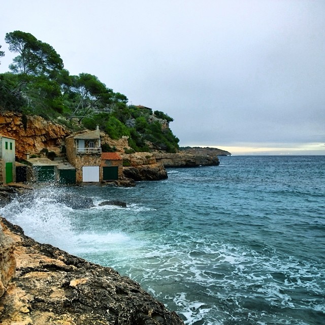 an ocean view showing some buildings on a cliff by the water