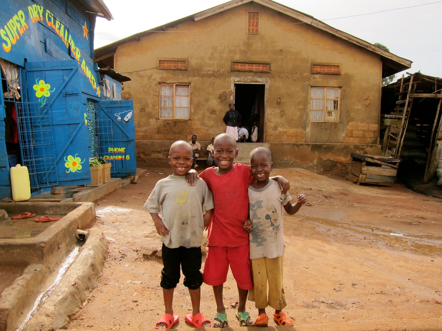 three boys in a village standing outside their house