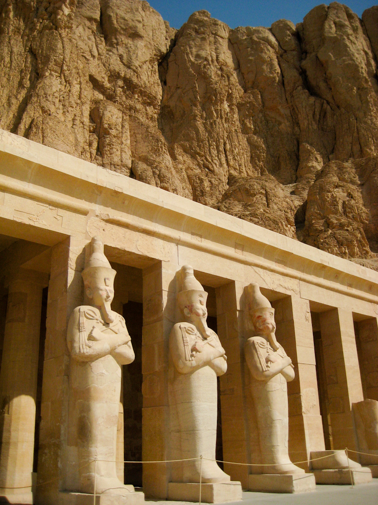 some statues are standing in front of a rock formation