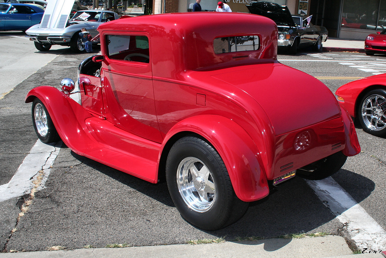 a bright red car is parked on the side of the road