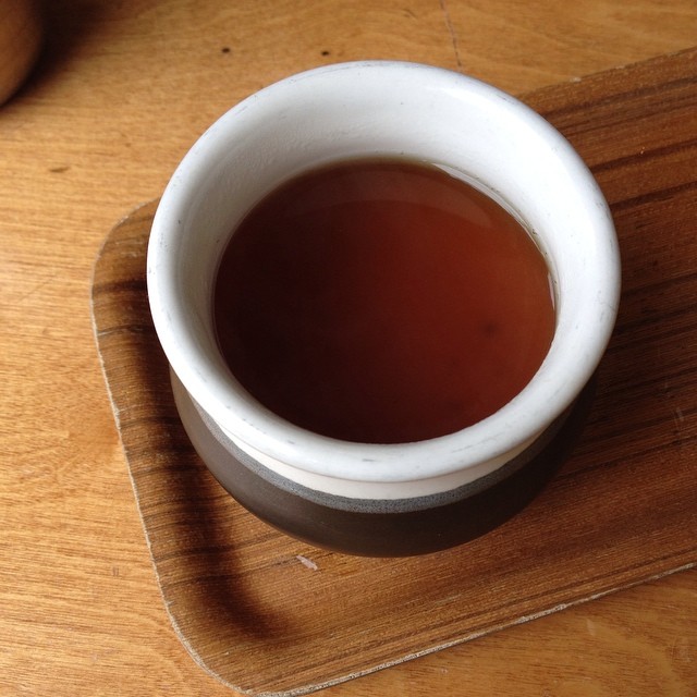 a cup of liquid sits on the wood table