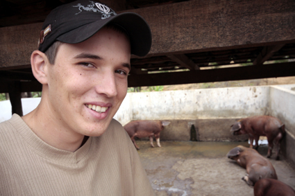 a young man smiling while standing in front of cows