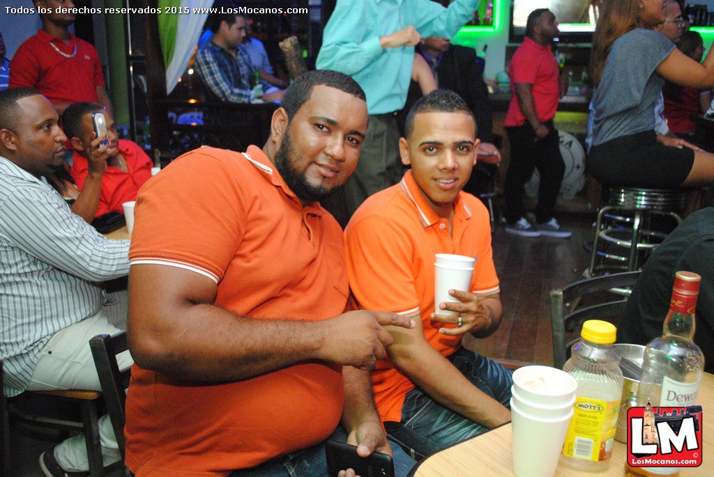 two men holding up drinks are sitting down