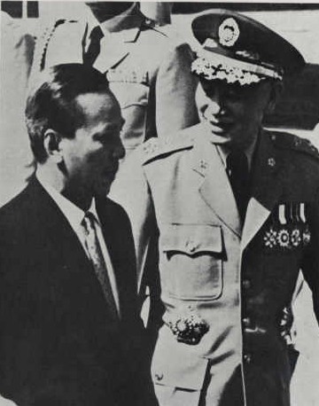 a man is standing next to another man in uniform