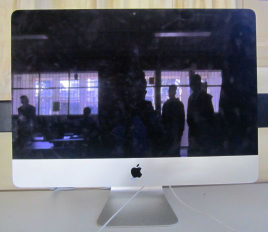 a apple computer with the reflection of people in the window