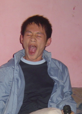 a young man sitting on top of a bed making a silly face
