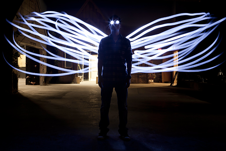 a person standing on a dark street with a glowing wings painted over their head