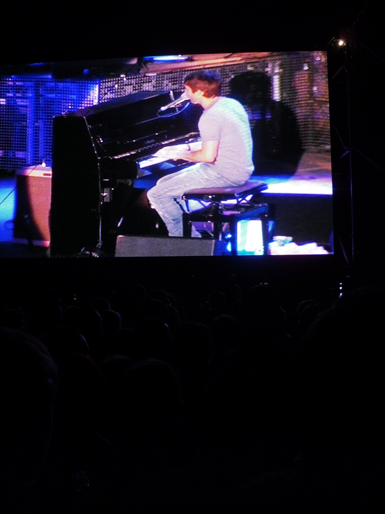 a guy playing a black piano on stage