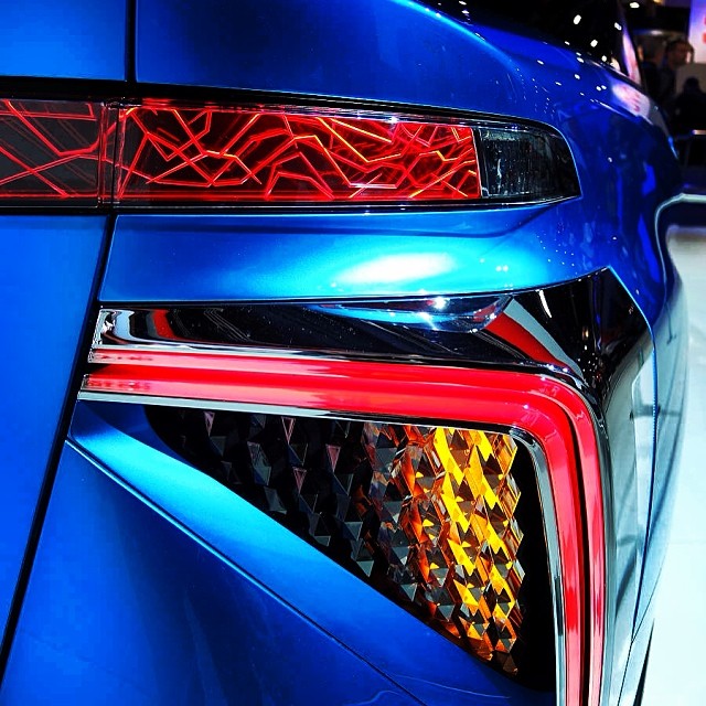the tail lights of a blue car at an automobile show