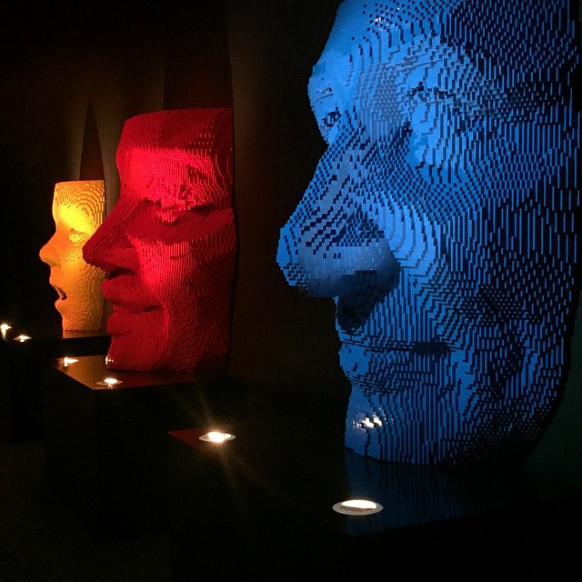 lit up sculpture head, with several other sculptures behind it