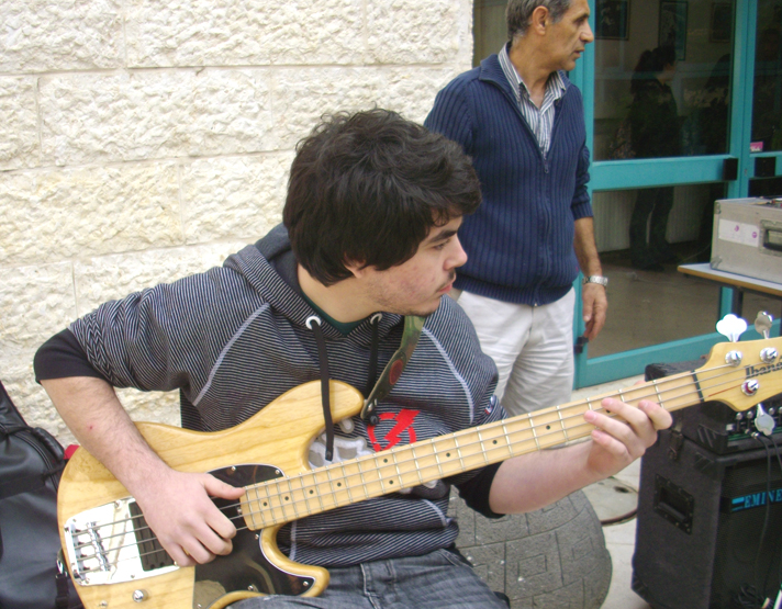 a young man plays a bass guitar for a crowd