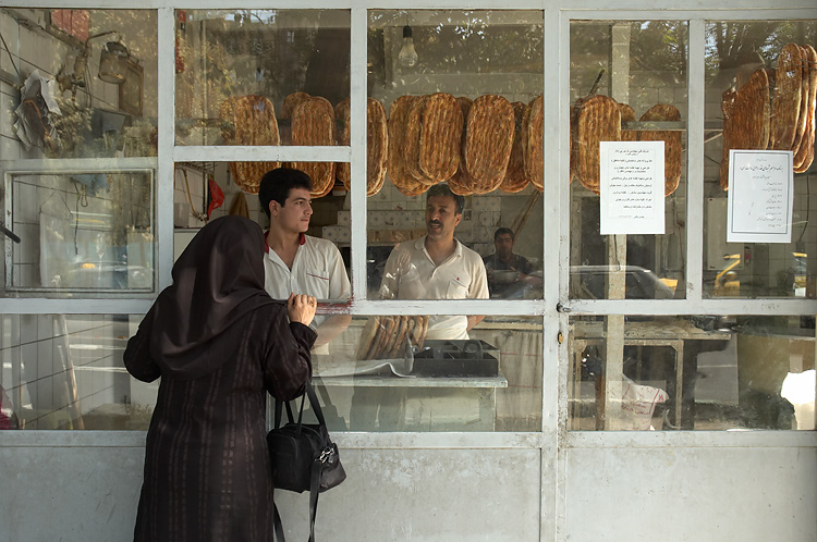 two women standing outside a store selling food