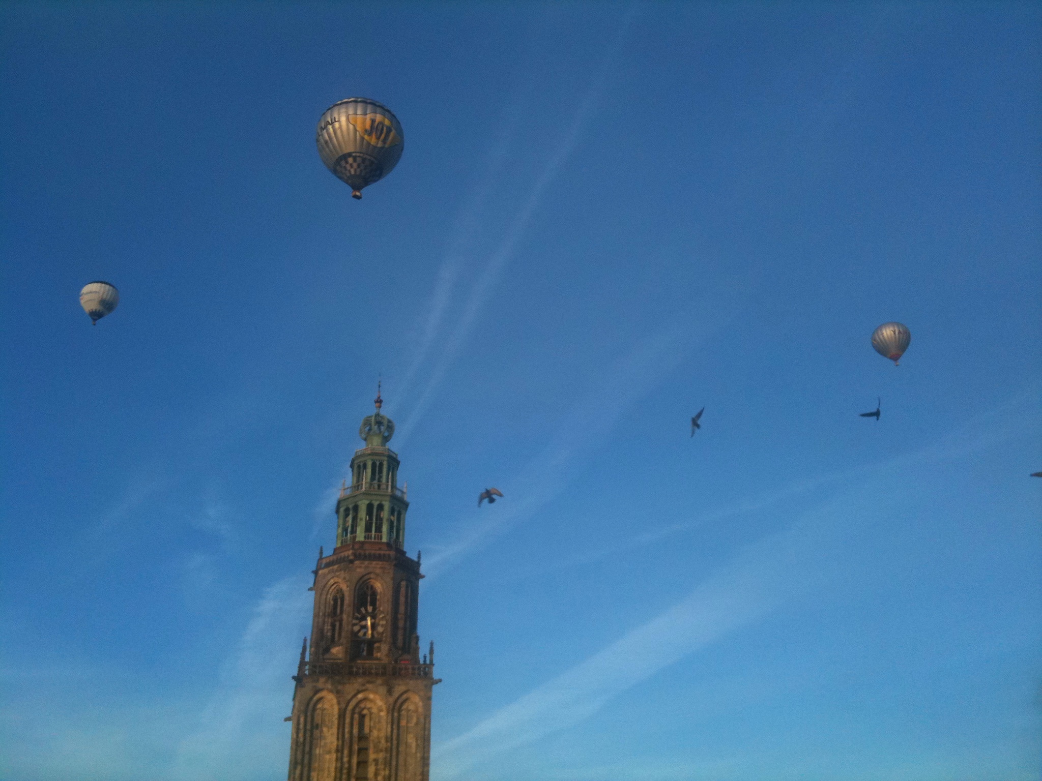 birds flying over a tall tower with a clock on it