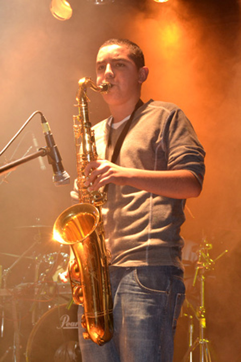 a man playing a saxophone while standing on stage