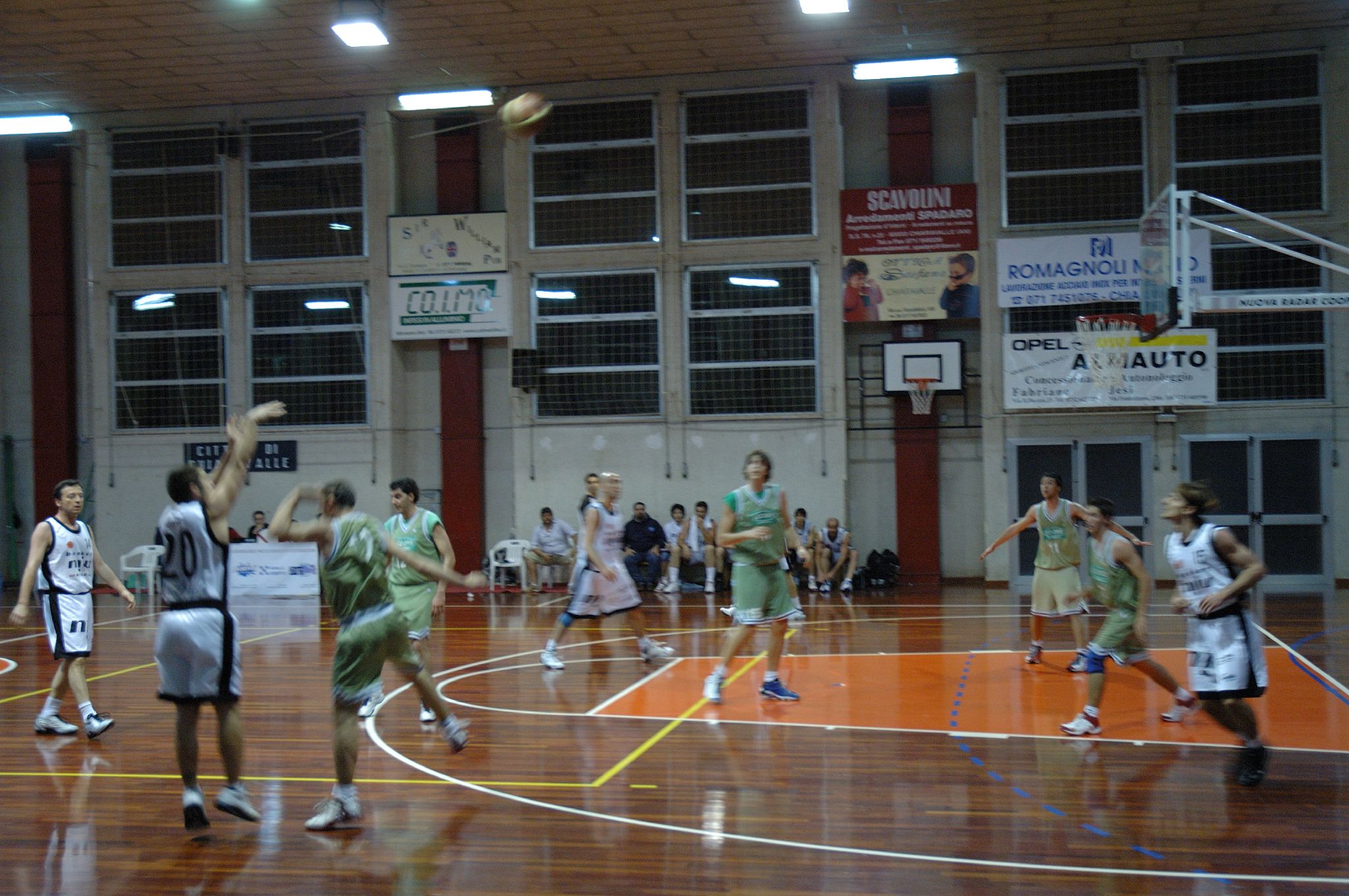 some girls in green are playing basketball inside a gym