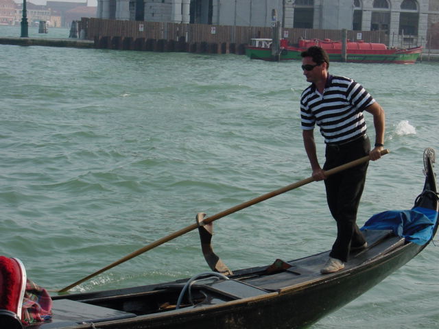 a man on a gondola in a canal with a tall pole