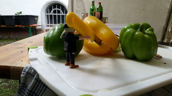 a doll figurine standing in front of peppers on a table